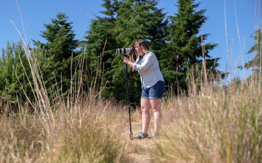 A woman taking a photograph using a monopod for stablization