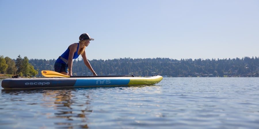 a stand up paddle boarder setting out on their paddling adventure in calm water and winds