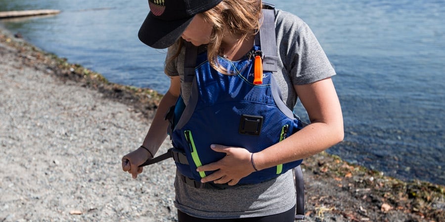 a kayaker fitting their pfd while on shore