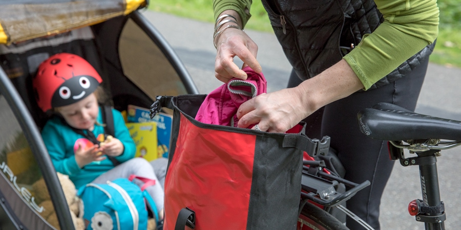 A mother taking her daughter's jacket out of the panniers on her bike