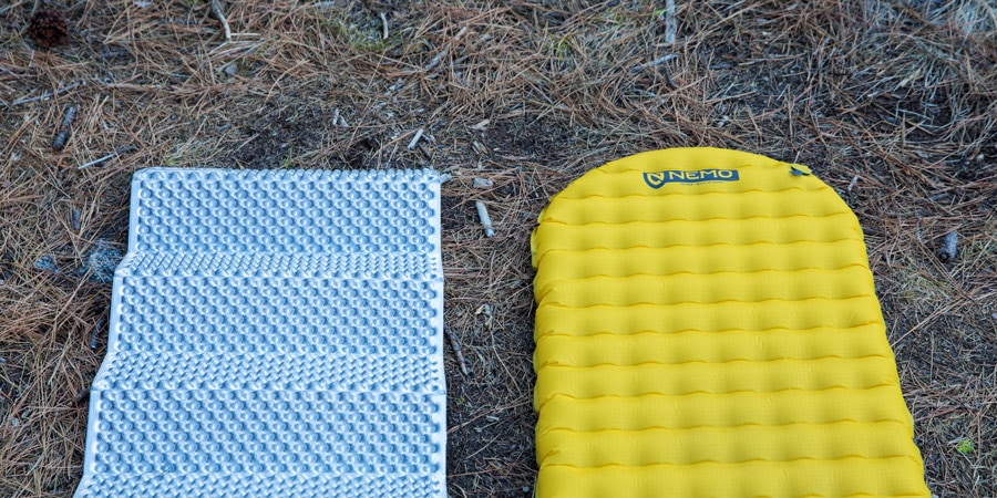 an ultralight closed foam cell sleeping pad set next to an ultralight air pad