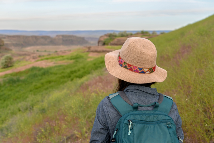 A woman wearing a sun hat hiking a trail in Eastern Washington