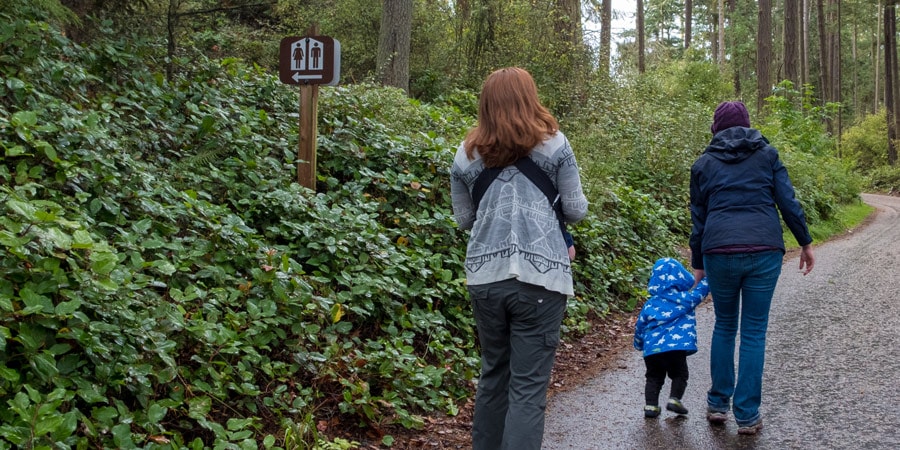 two mothers, one infant, and one toddler heading towards the restroom at a campground