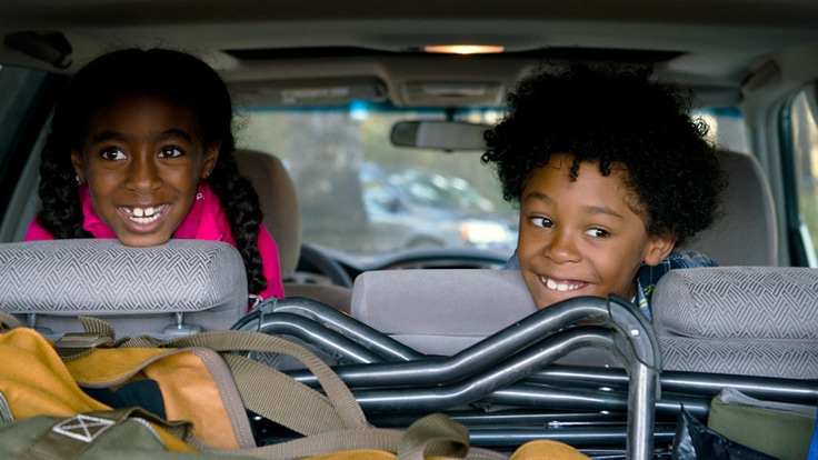 two kids in the back seat of a car, packed for a road trip